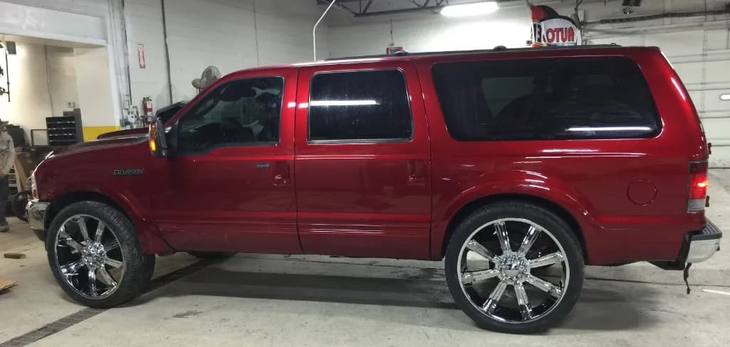 Candy-apple red Ford Excursion with oversized chrome rims in Jack's shop