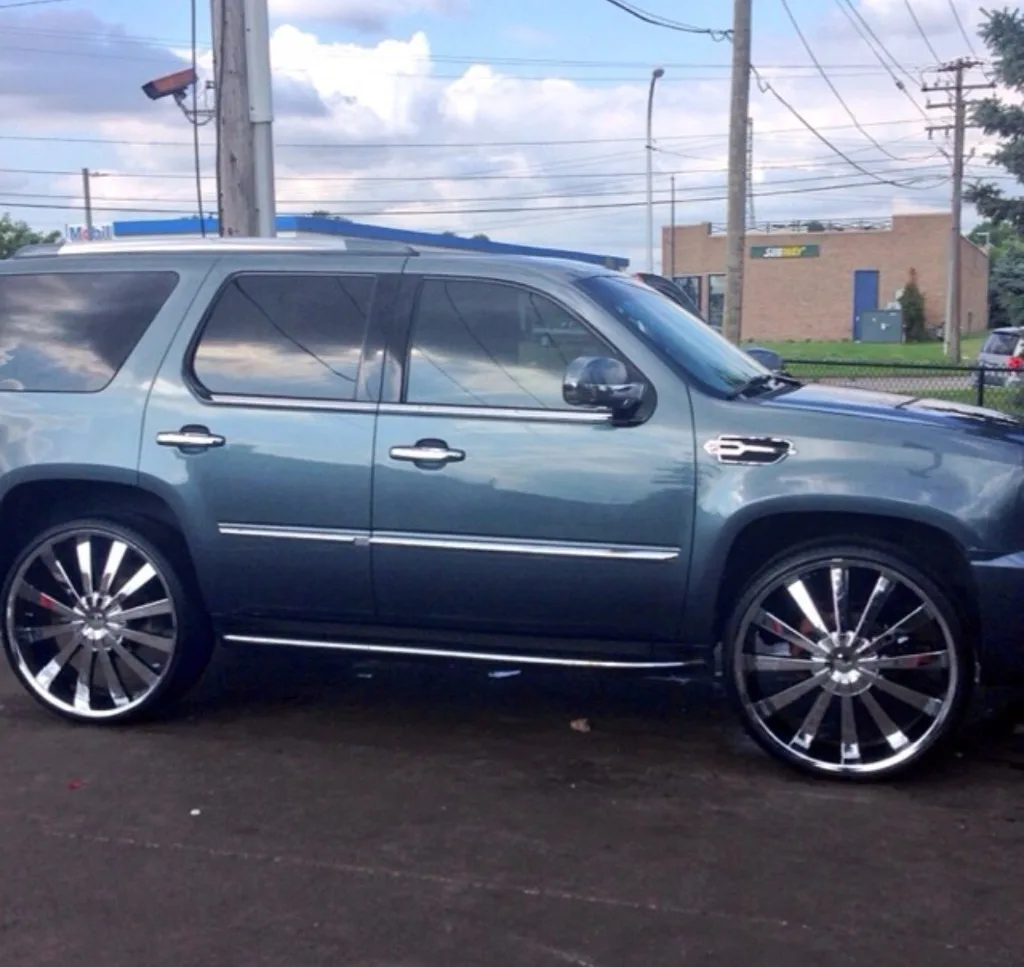 Dark Cadillac Escalade with large chrome multi-spoke wheels — custom rim install by Jack's